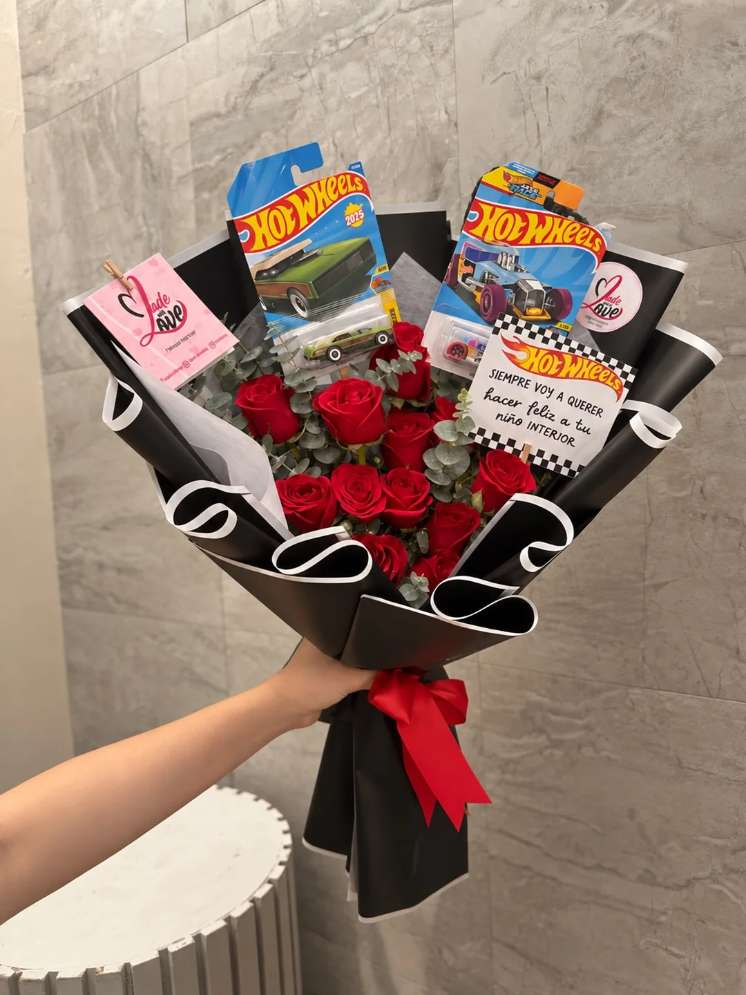 Ramo de rosas rojas con dos carritos Hot Wheels, tarjeta y envoltura negra
